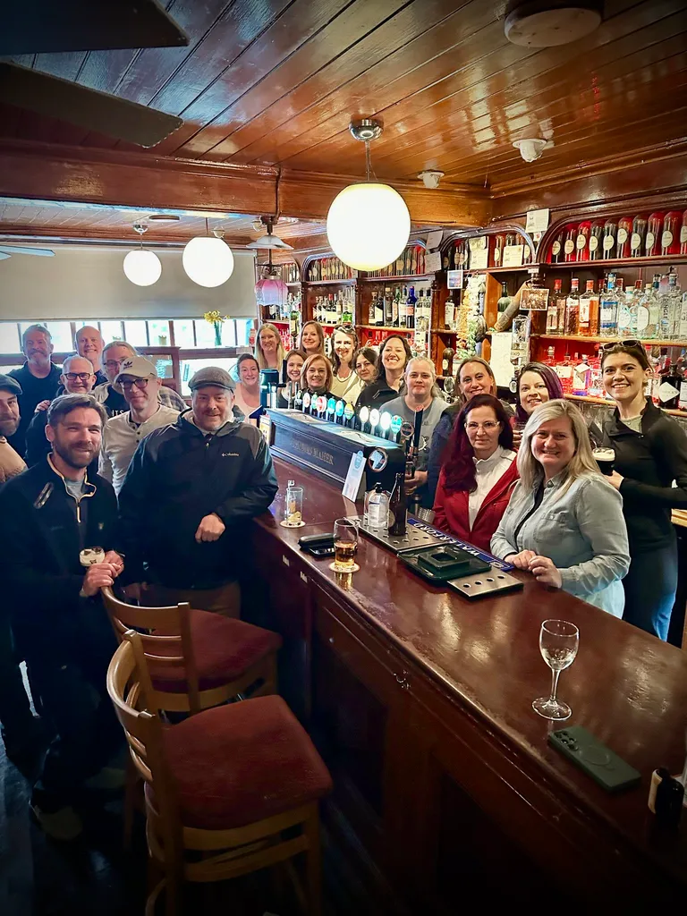 A group of past Ireland Pub Crawls travelers gathered at a traditional pub bar in Ireland