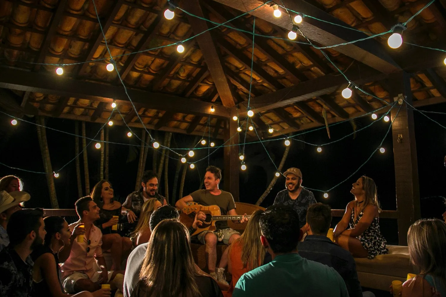 Musician performing acoustic set for travelers under string lights